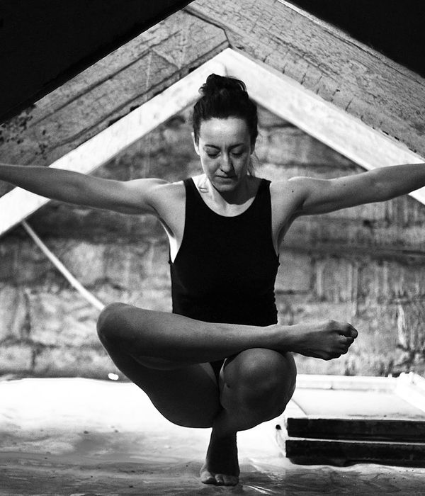 Woman in a graceful yoga pose in a dark room with amber light.